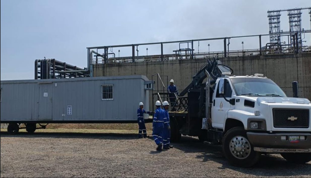 Modular trailer beside a truck with a hydraulic boom at an industrial site